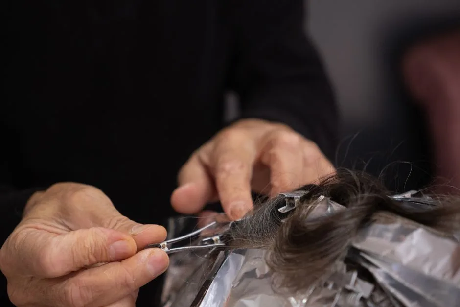 Detailed shot of a hairdresser applying hair color to a client's hair with foils.
